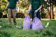 © Zamrznuti tonovi - Two volunteers collecting garbage in park are holding trash bags