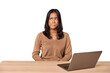 © Asier - Filipino woman at desk with laptop confused, feels doubtful and unsure.