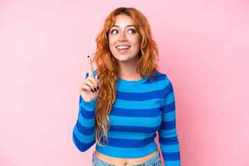 Wall Mural - young caucasian woman isolated on pink background intending to realizes the solution while lifting a