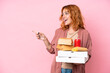 © luismolinero - Young caucasian woman holding fast food isolated on pink background pointing finger to the side and presenting a product