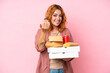 © luismolinero - Young caucasian woman holding fast food isolated on pink background inviting to come with hand. Happy that you came