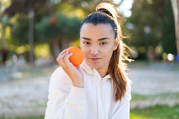 Poster - Young pretty brunette woman holding an orange