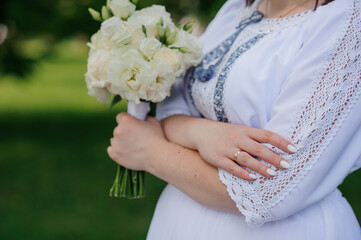 Wall Mural - Elegant Bride Holding White Flower Bouquet in a Lush Green Setting