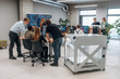 © standret - Big screen with code on the wall. People are in the office by the 3d printer