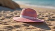 © Neeranat - A pink hat resting on the sand beside the ocean waves.