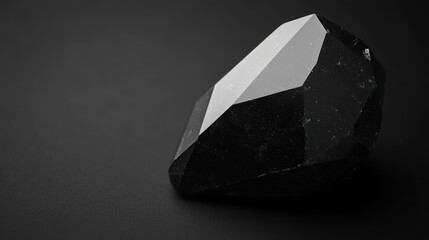Poster - A polished black crystal with sharp facets resting on a dark surface.