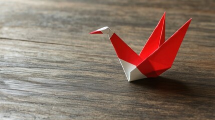 Poster - A red and white origami crane on a wooden surface, symbolizing peace and creativity.