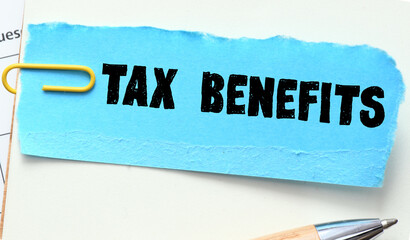 TAX BENEFITS words on a blue piece of paper in an office notebook.