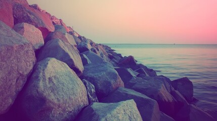 Aufkleber - A tranquil shoreline with large rocks and calm water under a pastel sky.