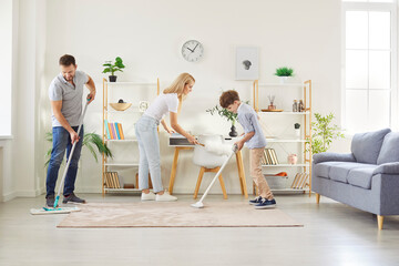 Young family of three - mother, father with little child boy cleaning house and wiping dust together in the living room at home. Family housework, housekeeping and household concept.