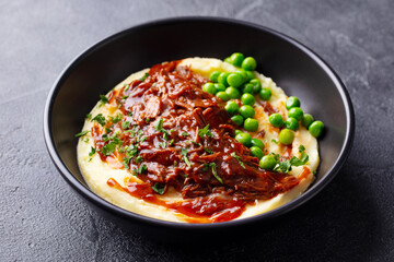 Wall Mural - Mashed potatoes with beef meat and green peas in bowl. Dark background. Close up.