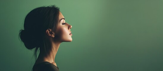 Wall Mural - Elegant profile portrait of serene young woman with closed eyes against soft green gradient background, featuring spacious empty copyspace for text.