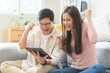 © KMPZZZ - Happy excited, smiling asian young couple love using tablet pc, great deal or business success, received or getting cash back, tax refund, good news by mail while sitting on floor at home.