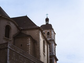 A historic church in Briançon, France, showcasing aged stone walls and a bell tower with a cross against a clear blue sky. Captures timeless European architectural charm.