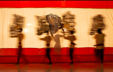 Wall Mural - Blur image of four player men moving with perform grand shadow play in front of white screen with main focus is on shadow of charactor behide the screen.