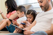 © Daniel Gonzalez/Stocksy - Kids using devices near parents