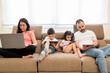 © Daniel Gonzalez/Stocksy - Concentrated family using various gadgets in living room
