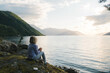 © Tanya Yatsenko/Stocksy - A girl sitting on the rocks with fjord view