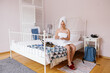 © Oleksii Syrotkin/Stocksy - Pretty young woman pouring moisturizing on cotton pad sitting on bed
