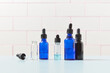 © Yaroslav Danylchenko/Stocksy - Various glass dropper bottles standing over tiled background