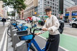 © Alvaro Lavin/Stocksy - Young professional unlocking bikeshare bicycle in new york city