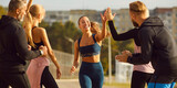 Sports and running races. Happy young woman runner giving high five to other people after successful result in race. Smiling Caucasian woman in sports outfit runs and greets spectators at finish line.