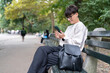 © Alvaro Lavin/Stocksy - Businesswoman using smartphone while relaxing on bench