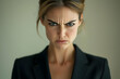 © Fazal - A strong expression of an angry businesswoman, isolated against a neutral backdrop, with emphasis on her facial features.