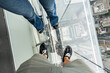 © Alvaro Lavin/Stocksy - Tourists wearing shoe covers standing on glass floor enjoying view