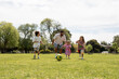 © Stephanie Tamir/Stocksy - Dad with his kids playing soccer in a park