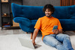 © ViDi Studio - Young IT man in casual clothes sit on blue sofa couch hold mobile cell phone use work on laptop pc computer stay home hotel flat rest relax spend free spare time in living room indoor Lounge concept