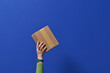 © Marc Tran/Stocksy - Hand Holding Cardboard Box Against Vibrant Blue Background