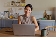 © BONNINSTUDIO/Stocksy - Woman working from home using laptop in kitchen