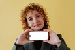 © BONNINSTUDIO/Stocksy - Woman showing smartphone with blank screen on yellow background