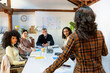 © Jimena Roquero/Stocksy - group of coworkers in business meeting listening to project leader