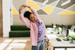 © Maria Vitkovska - Smiling African American manager stretching arms at workplace in modern office