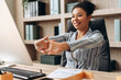 © Maria Vitkovska - Smiling businesswoman stretching arms at office desk