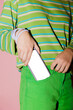 © BONNINSTUDIO/Stocksy - Woman putting smartphone with blank screen in green jeans pocket