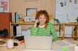 © BONNINSTUDIO/Stocksy - Woman talking on phone and working on laptop in home office