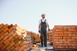 © Serhii - Construction worker man in work clothes and a construction helmet. Portrait of positive male builder in hardhat working at construction site