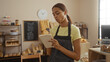 © Krakenimages.com - Young woman working in a bakery shop taking notes with a notepad, surrounded by shelves of bread and pastries in a cozy indoor setting