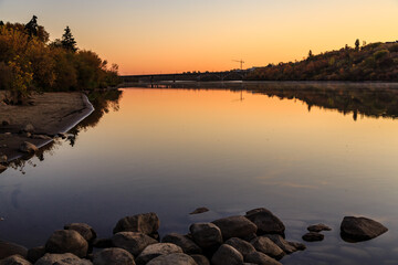 Wall Mural - a beautiful sunset over a lake with a bridge in the background