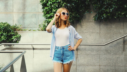 Poster - Beautiful modern young woman looking away standing on city street in summer wearing shorts, shirt