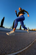 © Javier Díez/Stocksy - Energetic sportswoman jumping while running on asphalt road