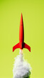 © Marcos Osorio/Stocksy - Red rocket takes off, releasing smoke against a bright background