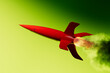 © Marcos Osorio/Stocksy - Red rocket takes off, releasing smoke against a bright background