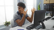 © Krakenimages.com - Young hispanic man gesturing while working at a modern office desk with computer and papers