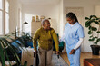 © BONNINSTUDIO/Stocksy - Nurse assisting elderly woman using crutches at home