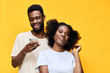 © SHOTPRIME STUDIO - A joyful young couple posing together on a bright yellow background, showcasing modern casual attire and playful emotions, perfect for lifestyle themes