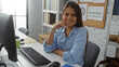 © Krakenimages.com - Young woman smiling at her workplace in an office setting seated at a desk near a computer and bookshelves